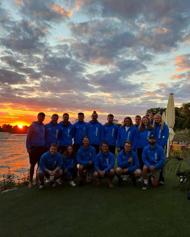 Several people with the same clothes in front of a lake at sunset