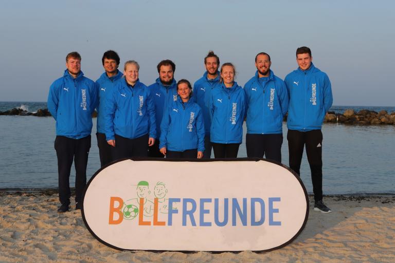 L'équipe Ballfreunde sur la plage avec une bannière