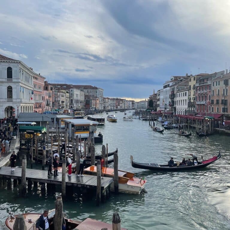 Town with old buildings and a river and many boats at dusk