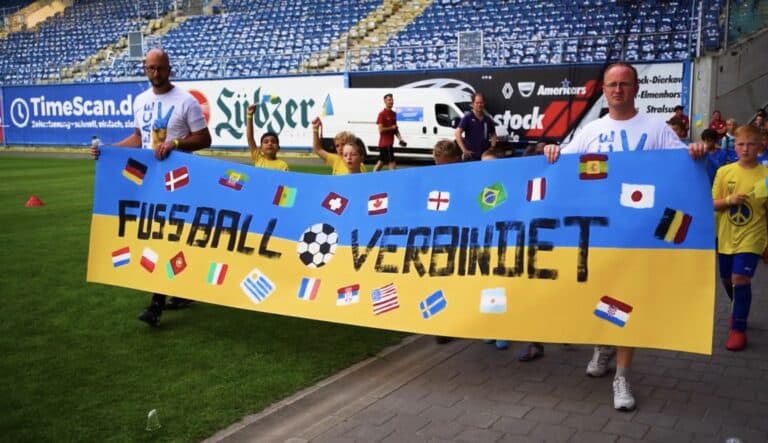 Flera personer på fotbollsstadion håller plakat