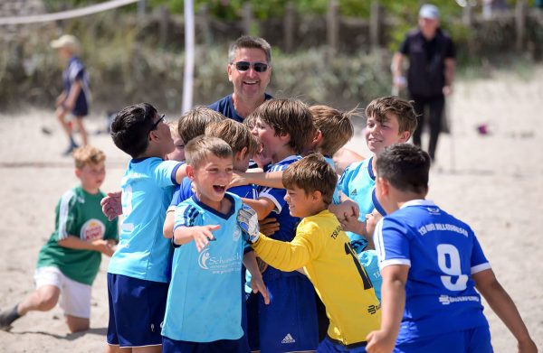 Jublende barn på en strandfotballturnering på Østersjøen.