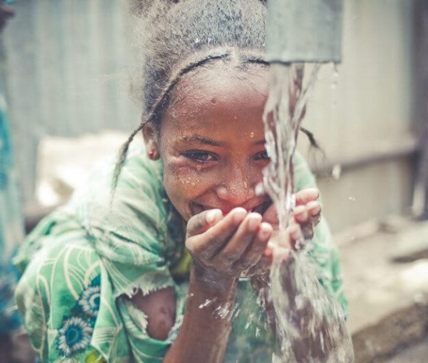 Une petite fille africaine est heureuse de boire de l'eau