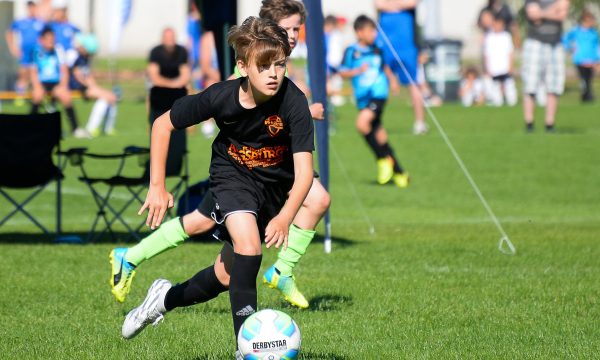 Scène de tournoi de football : un joueur guide le ballon lors de la mini-coupe du monde des amis du ballon.