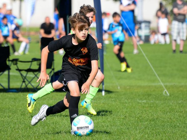 Scène de tournoi de football : un joueur guide le ballon lors de la mini-coupe du monde des amis du ballon.